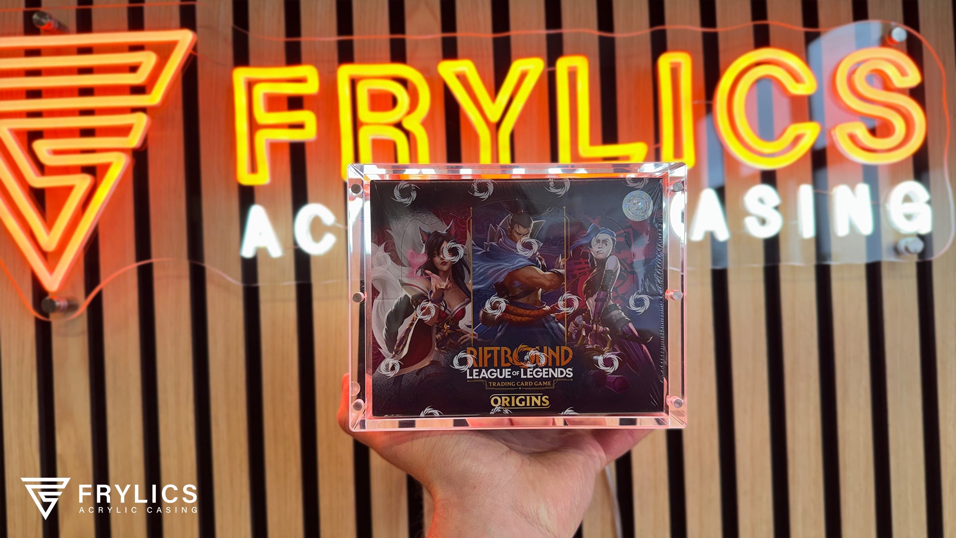 Riftbound Booster Box in Frylics Acryl Case gemaakt voor houten achterwand met Frylics logo als sfeerbeeld